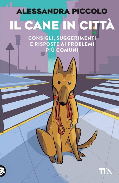 Sulla copertina di Il cane in città di Alessandra Piccolo c'è l'illustrazione di un cane con le orecchie dritte che tiene in bocca un guinzaglio mentre aspetta a un incrocio in città