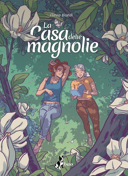 Sulla copertina de La casa delle magnolie di Flavia Biondi ci sono due donne sdraiate sull'erba sotto un albero di magnolie; una legge un libro e l'altra la guarda sorridente
